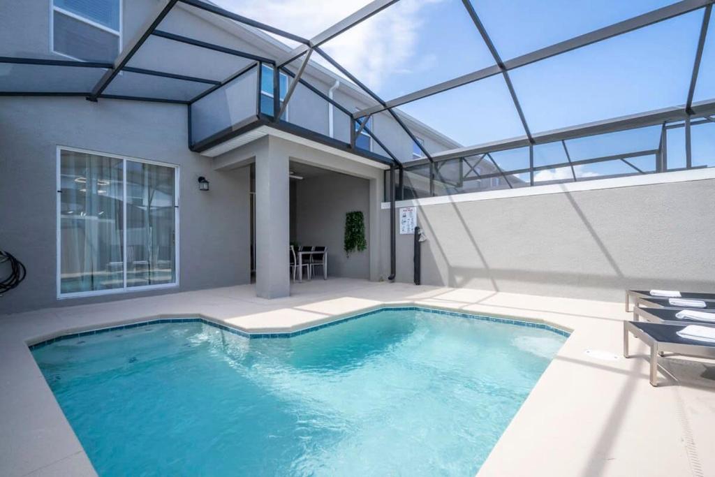 una piscina en una casa con techo de cristal en WonderFul 4Bd w Pool Close to Disney at StoreyLake 2669, en Kissimmee