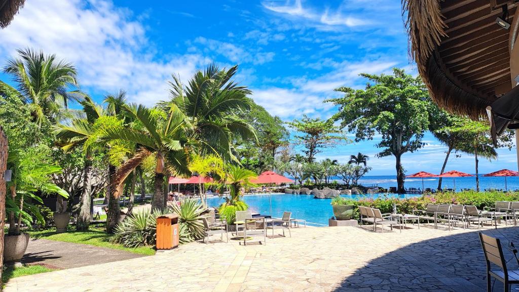 un complexe avec une piscine, des chaises et des palmiers dans l'établissement TAHITI - Condo Lafayette Beach, à Arue