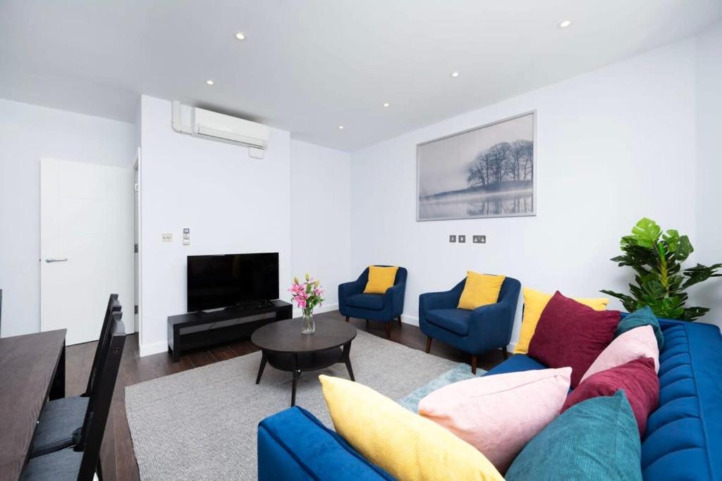 a living room with a blue couch and chairs at Stylish 3BR Flat in the Heart of Soho London in London