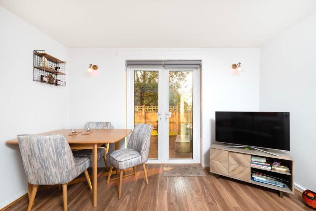 une salle à manger avec une table et une télévision dans l'établissement Charming 1BR flat with patio perfect for couples, à Londres