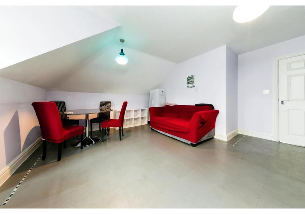 uma sala de estar com um sofá vermelho e uma mesa em Chic Croydon 2BR Flat - Free Parking em Purley
