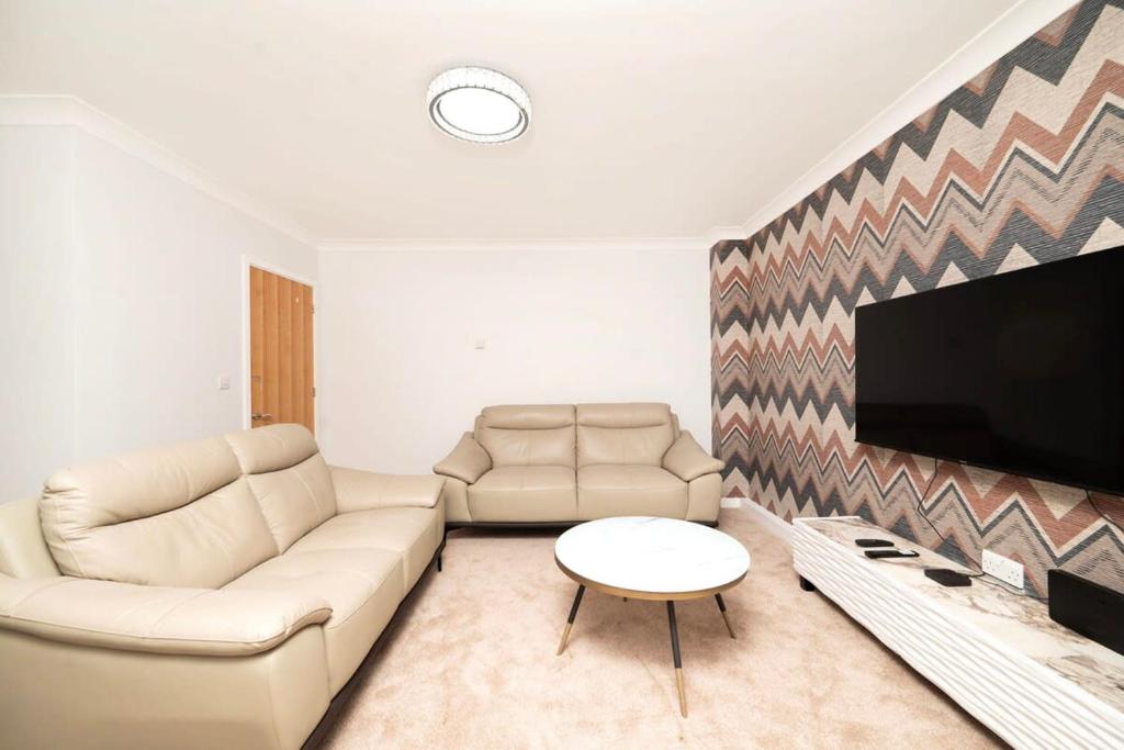 a living room with a couch and a flat screen tv at Chic and Spacious 3BR Family Home with Garden in Northolt