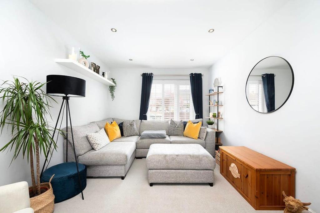uma sala de estar com um sofá e um espelho em Charming 2BR House with Garden em Shepperton