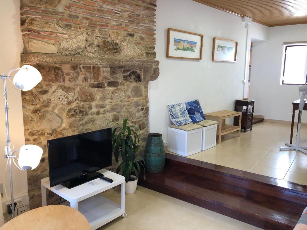 a living room with a tv and a stone wall at Apartamento 1 Penedo in Sintra
