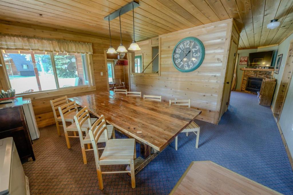 a dining room with a large wooden table and a clock at Alpine Star Lodge in West Yellowstone