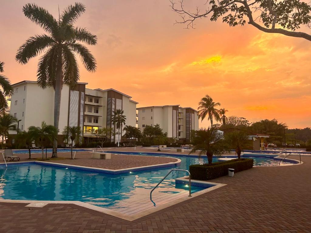 einen Pool in einem Resort mit Sonnenuntergang im Hintergrund in der Unterkunft Casa Arrecife de Sueños in Bejuco
