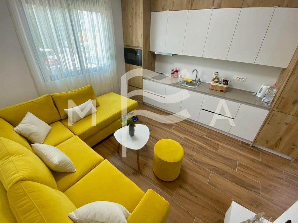 uma sala de estar com um sofá amarelo e uma cozinha em Sunny Moon 510 em Durrës