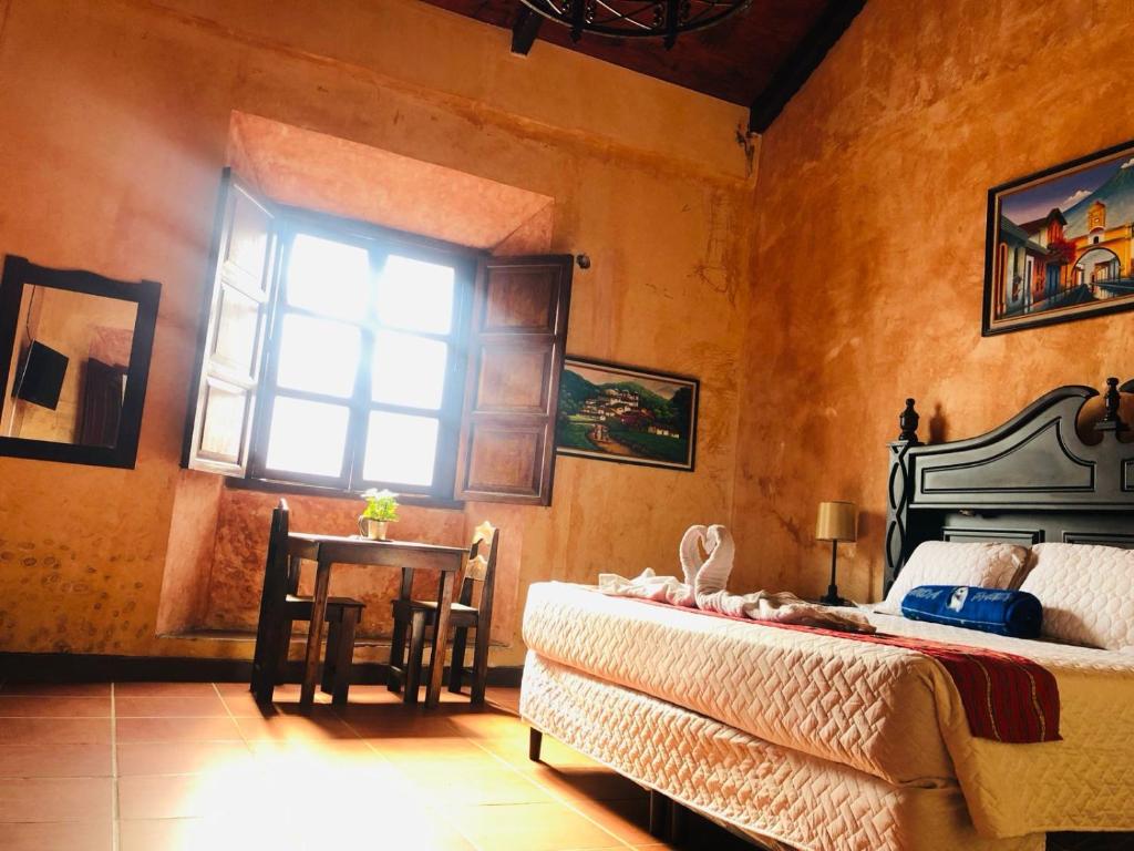 a bedroom with a bed and a table and a window at Casa Familiar San Sebastian in Antigua Guatemala