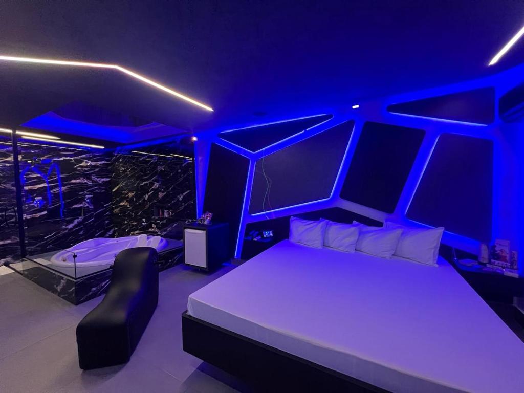 Prestige Motel 4 في سوروكابا: غرفة نوم بسرير مع اضاءة زرقاء