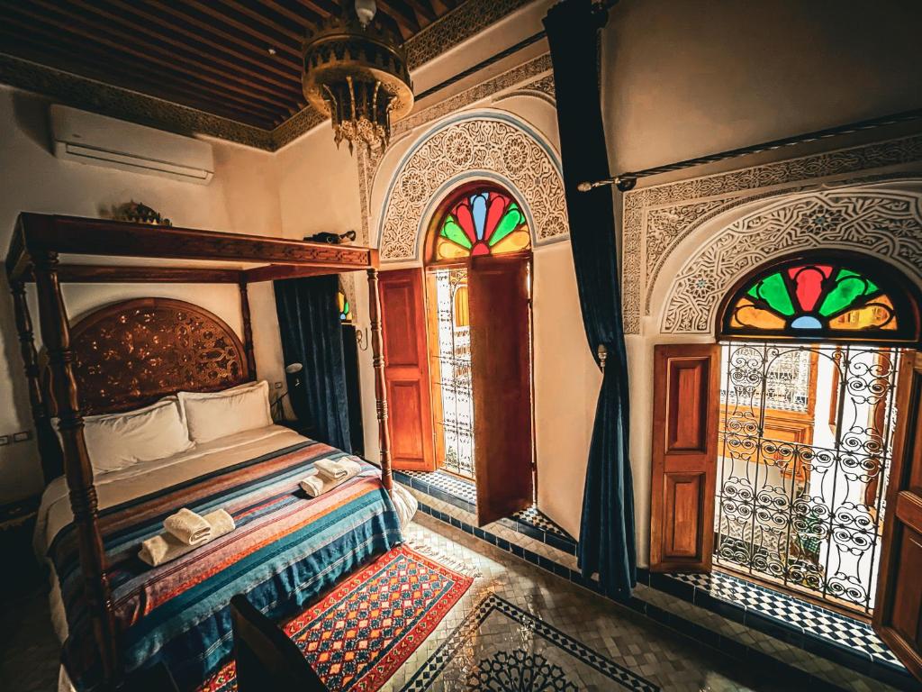 1 dormitorio con 1 cama y 2 vidrieras en Riad Rasia en Fez