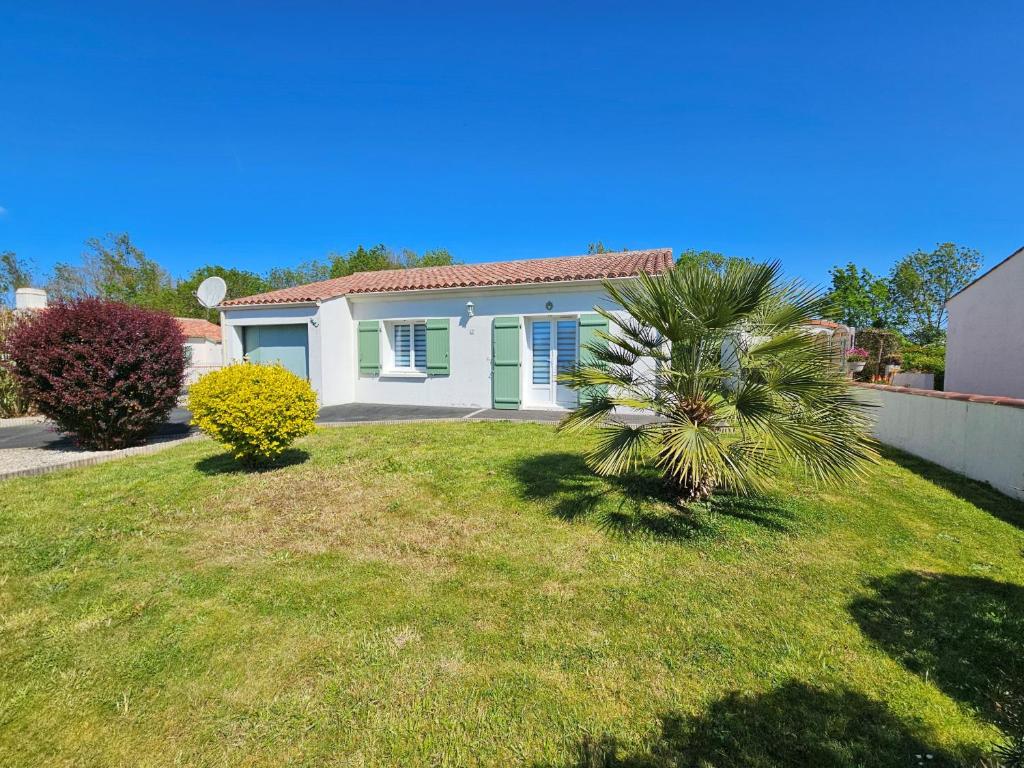 une petite maison blanche avec un palmier dans une cour dans l'établissement Charmante maison entre mer et campagne, calme, proche plages, Saint-Michel-en-l'Herm, 4 pers. - FR-1-476-41, à Saint-Michel-en-lʼHerm