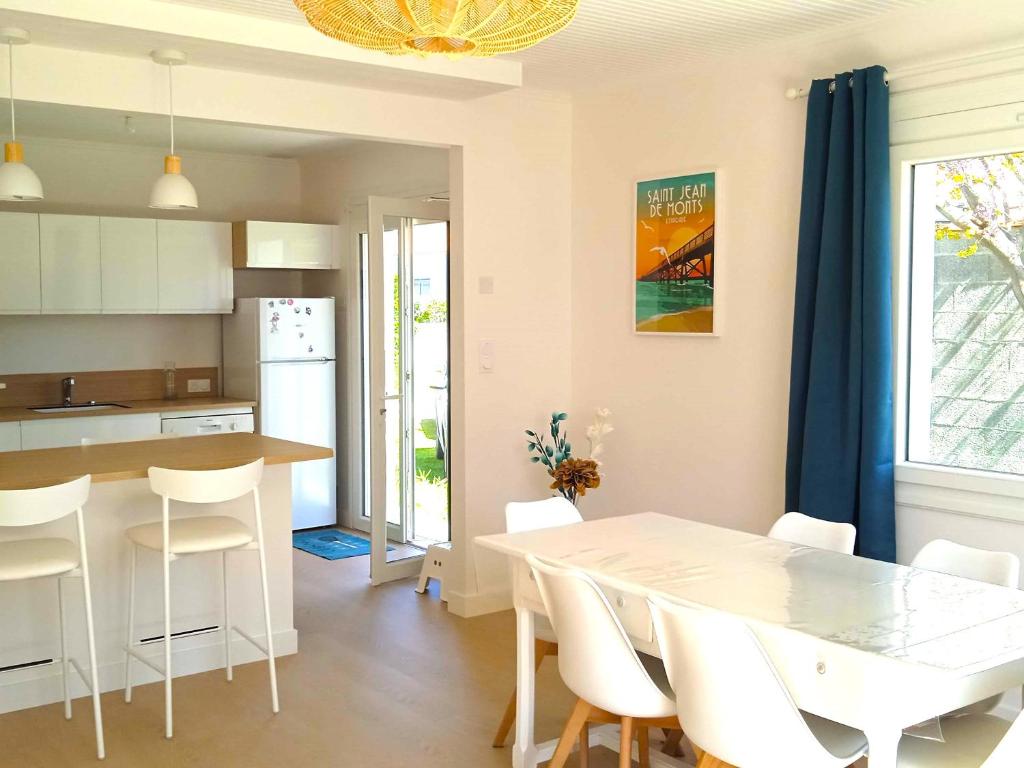 une cuisine et une salle à manger avec une table et des chaises blanches dans l'établissement Maison Cosy, Rénovée, Proche Plage et Centre, Jardin, Animaux Bienvenus - FR-1-652-19, à Saint-Jean-de-Monts