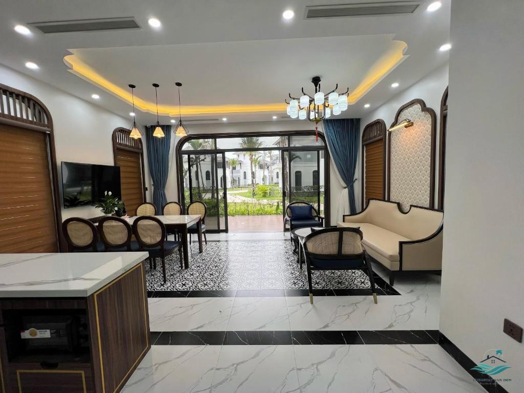 een woonkamer met een tafel en stoelen en een bank bij Rosa Villa - Sonasea - Vân Đồn 