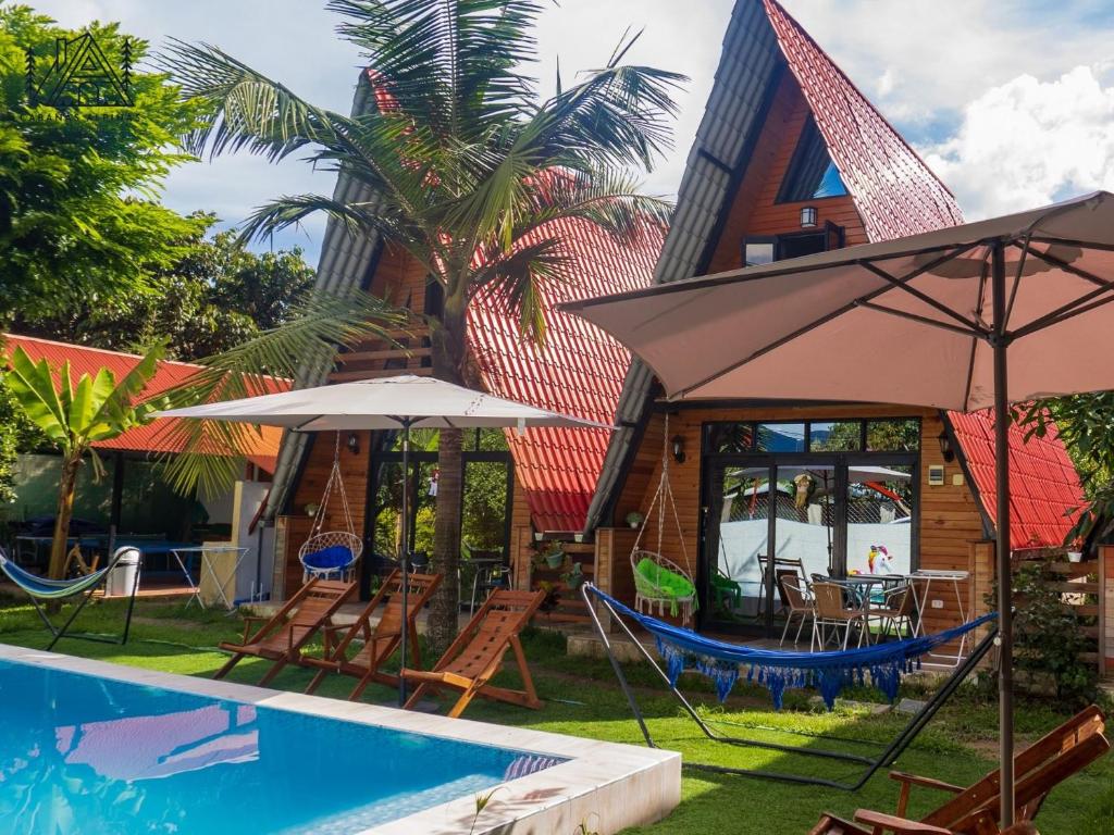 a resort with a swimming pool with chairs and an umbrella at Cabañas Alpinas en Oxapampa in Oxapampa