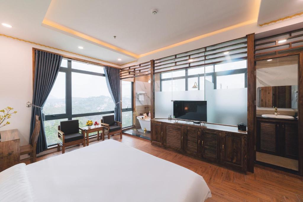 een slaapkamer met een groot bed en een televisie bij Greenview Hotel DaLat in Da Lat
