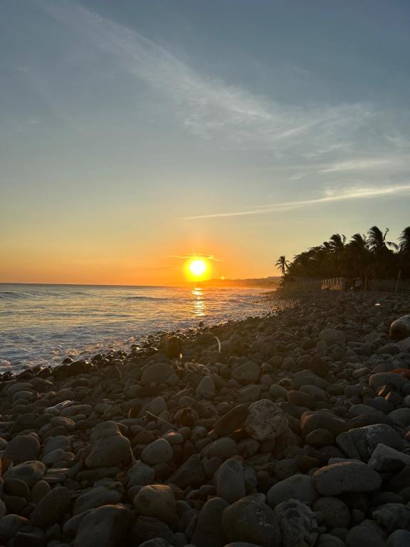 een zonsondergang op een strand met rotsen en palmbomen bij Punta Chilama in La Libertad