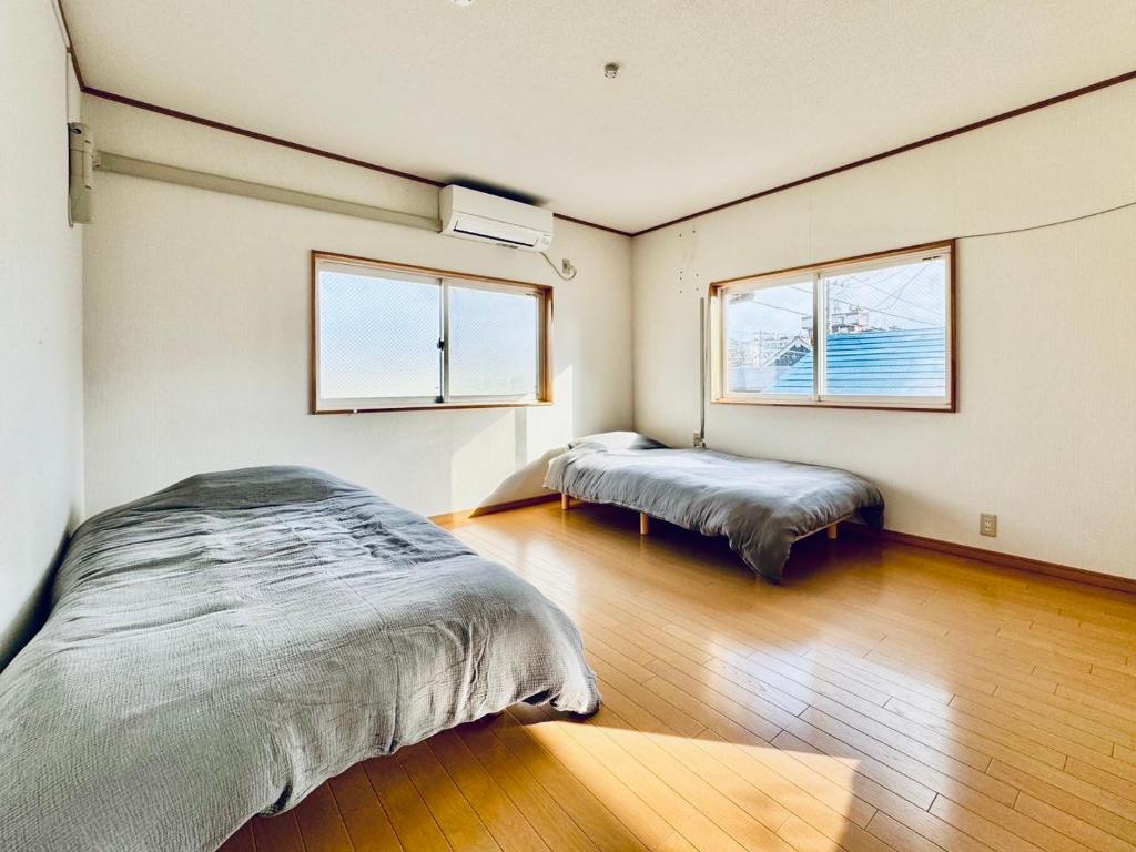 a bedroom with two beds and two windows at SUBAKO（yado＆community space） in Yurihonjo