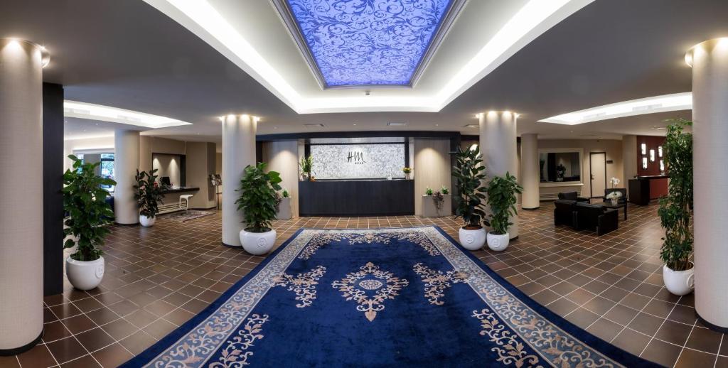 a lobby with a blue rug and potted plants at Hotel Mirage in Florence