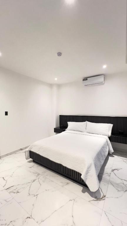 een witte slaapkamer met een bed en een witte muur bij MantaSurf Hotel in Tarqui