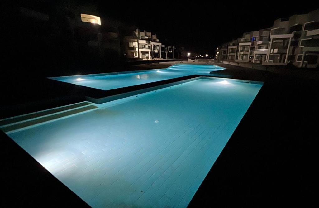 New Chalet Sea & Pool view Ras Sedr شاليه جديد دور ارضي في راس سدر في رأس سدر: حمام سباحة في الليل مع أضواء زرقاء