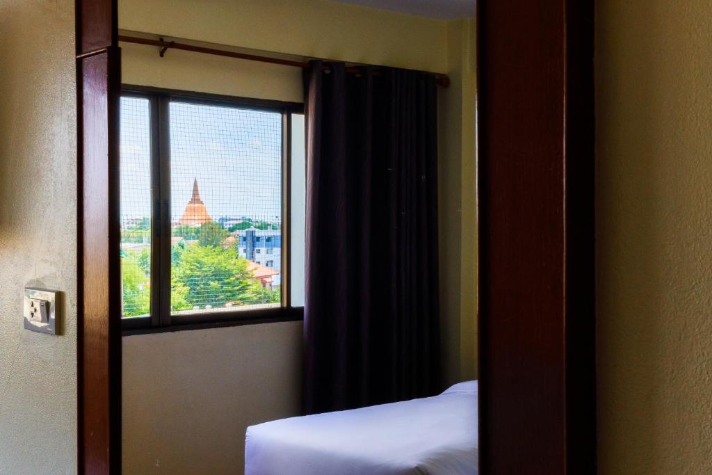 Habitación con ventana, cama y espejo. en River Hotel - The Outstanding Venues Nakhon Pathom 