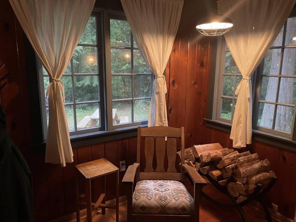 Habitación con silla, mesa y ventanas en Springbrook · Cozy 2BR Mt. Hood Cabin, Fireplace & Retro Kitchen, en Mount Hood Village