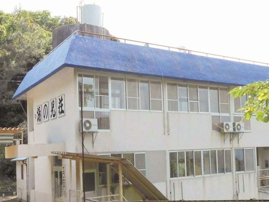 um grande edifício branco com um telhado azul em エコホテル　湯の児荘 em Mizumata