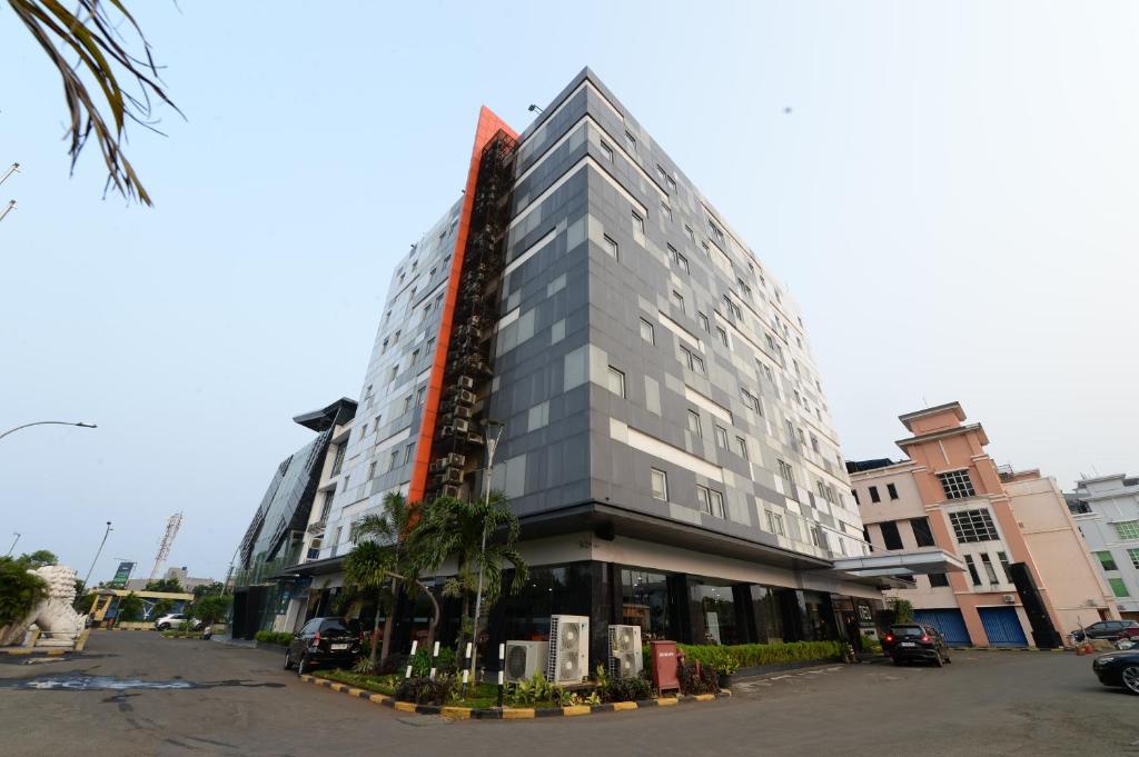 um edifício cinza alto com palmeiras em frente em HORU HOTEL MANGGA DUA SQUARE em Jacarta