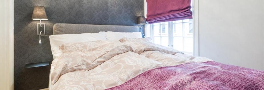 ein Bett mit einer rosa Decke und einem Fenster in der Unterkunft Boe Apartment Hotel in Egersund