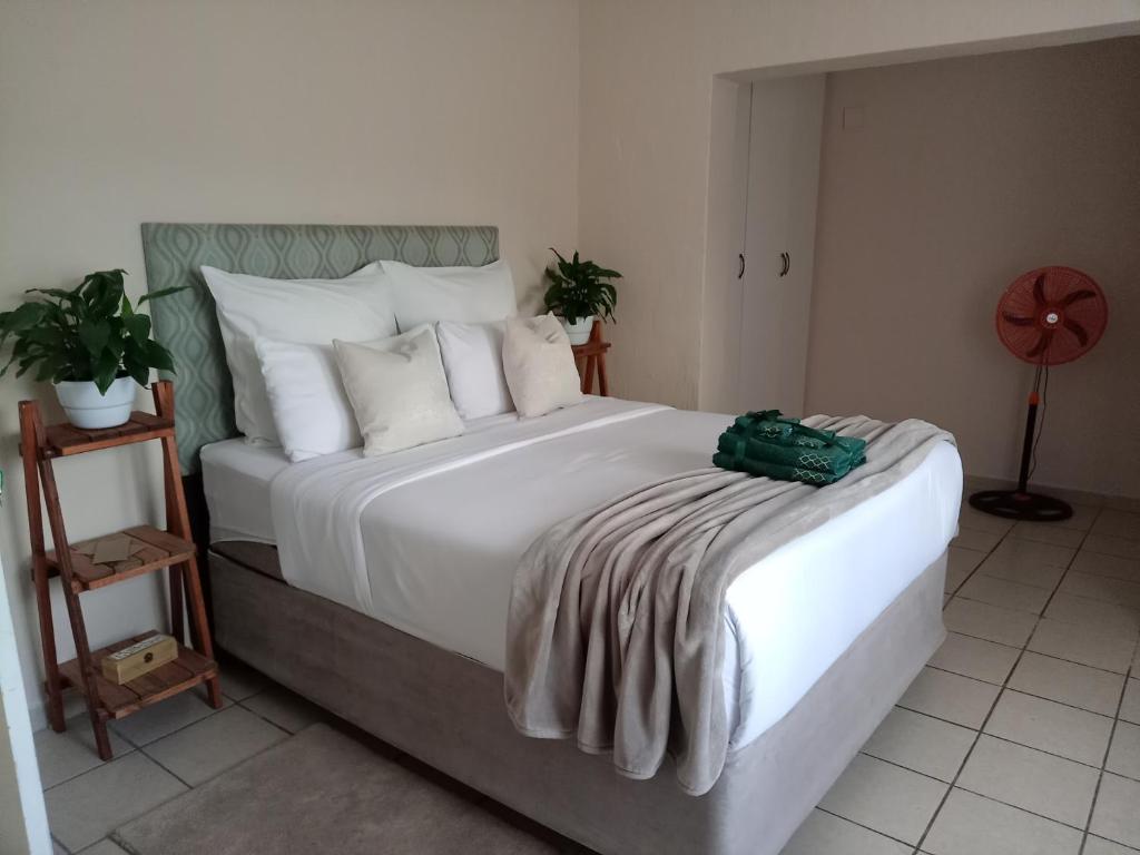 a bedroom with a white bed with a green bag on it at Olivia Pines Guesthouse in Krugersdorp