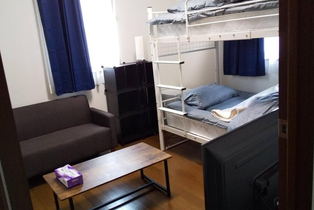 um pequeno quarto com um beliche e um sofá em スターリースカイズ那須店 em Nasu