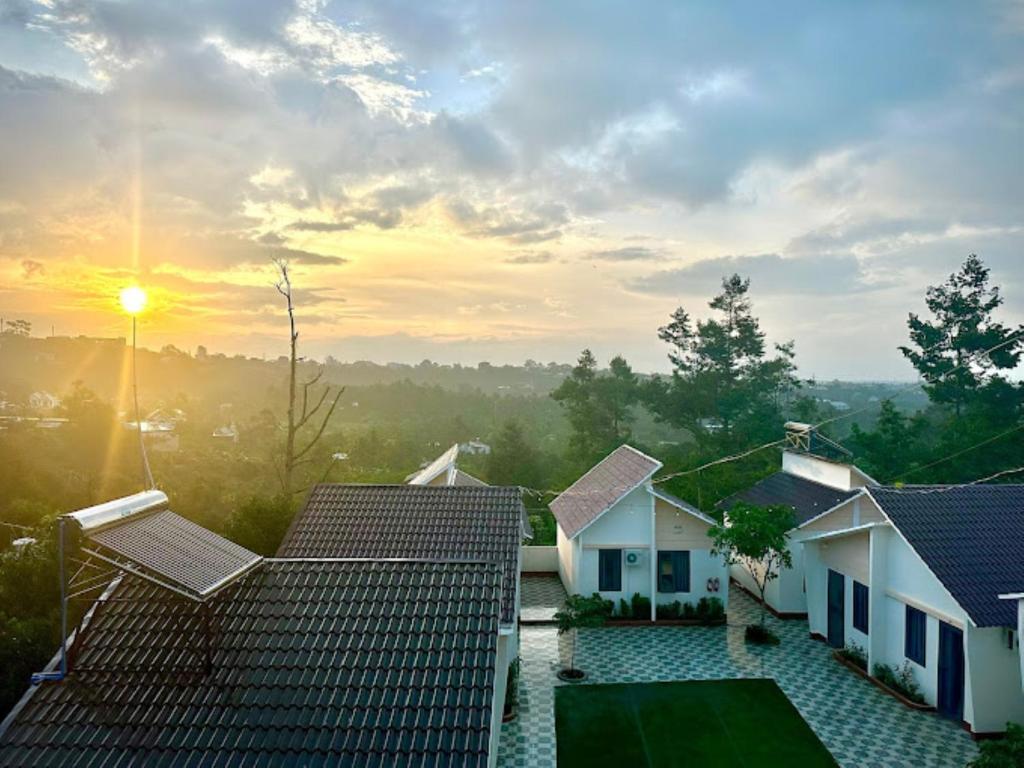 einen Blick auf die Dächer der Häuser mit Blick auf den Sonnenuntergang im Hintergrund in der Unterkunft ĐAM MÊ HOMESTAY in Bảo Lộc