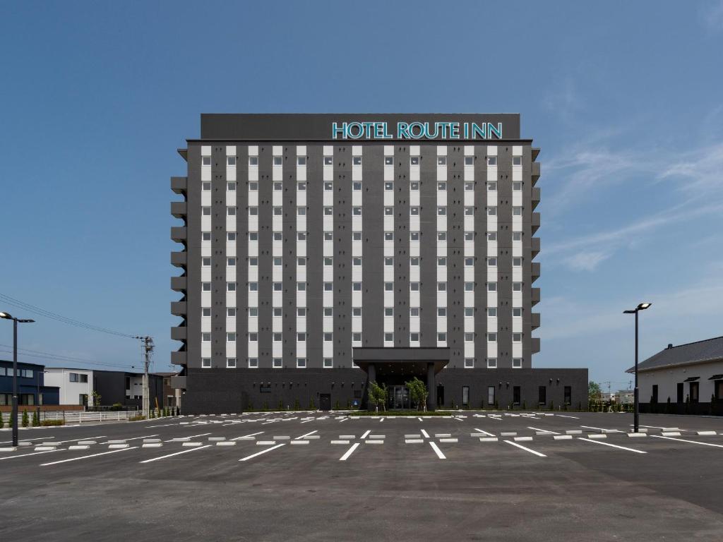 um edifício de hotel com um parque de estacionamento em frente em Hotel Route Inn Tokushima Airport -Matsushige Smartinter- em Matsushige
