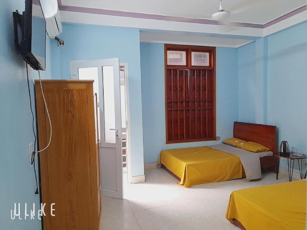 a bedroom with a yellow bed and blue walls at Nguyên căn Homestay 4 phòng ngủ sát biển in Sầm Sơn