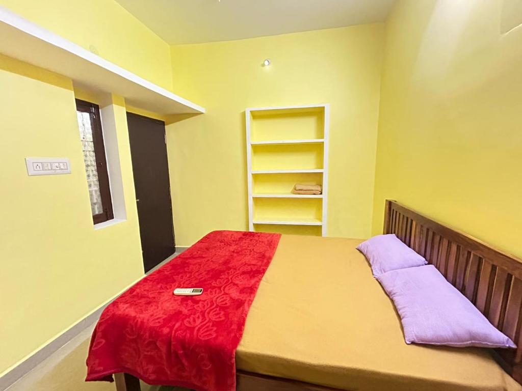 a bedroom with a bed with a red blanket on it at SELVAS BUDGET STAY in Pondicherry