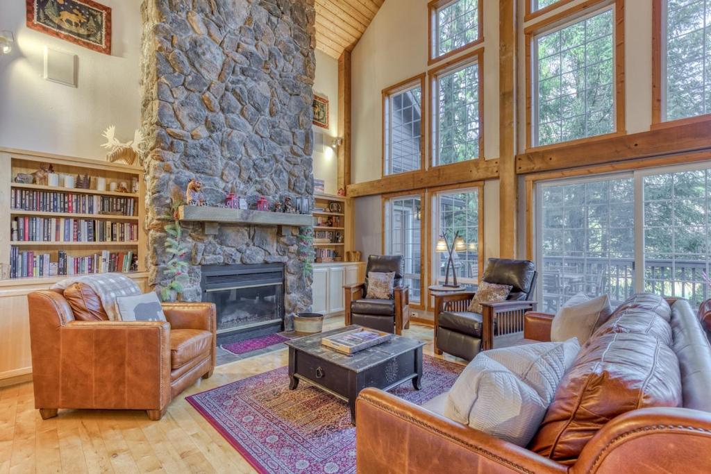 un soggiorno con mobili in pelle e camino in pietra di Lazy Bear Lodge · Spacious 6BR Lodge with Chef's Kitchen, Hot Tub, Golf Views and more a Mount Hood Village