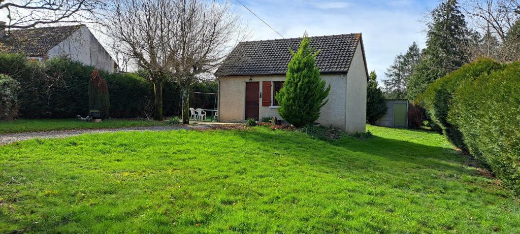 une petite maison dans une cour avec une pelouse verte dans l'établissement Le LILAS, à Éguzon-Chantôme