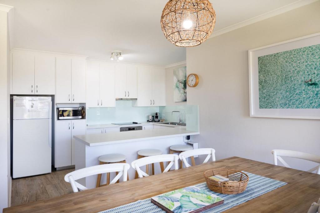 a kitchen with white cabinets and a table and chairs at Fathoms 8 in Mollymook