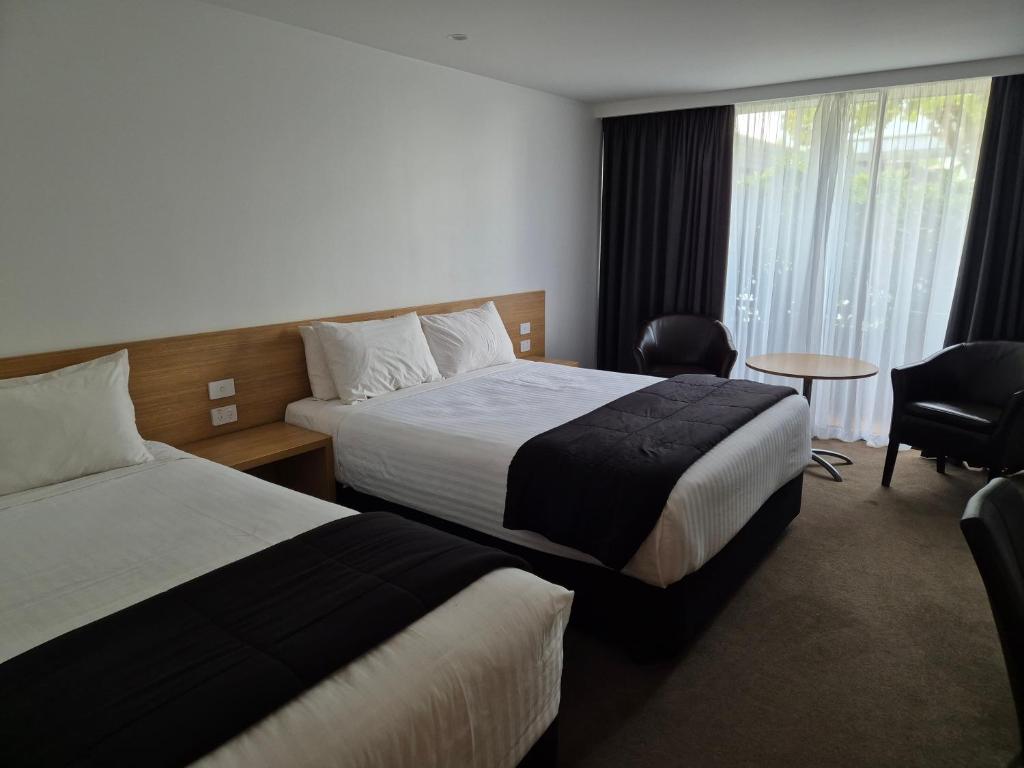 Habitación de hotel con 2 camas y mesa en Auto Lodge, en New Plymouth
