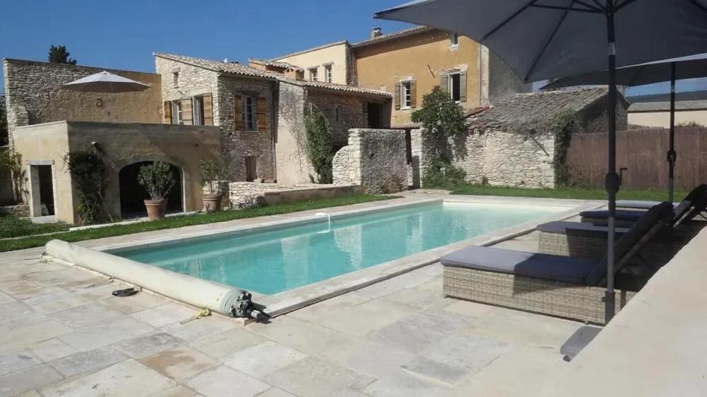 - une piscine avec un parasol en face d'une maison dans l'établissement Villa spacieuse à Saint-Saturnin-lès-Apt avec piscine privée 350 m², à Saint-Saturnin-lès-Apt