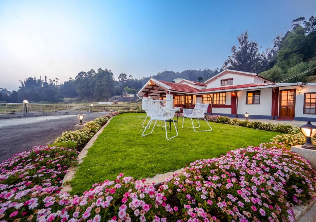 ein Haus mit zwei Stühlen und Blumen im Hof in der Unterkunft Lauriston Villa Ooty by VOYE HOMES in Udagamandalam