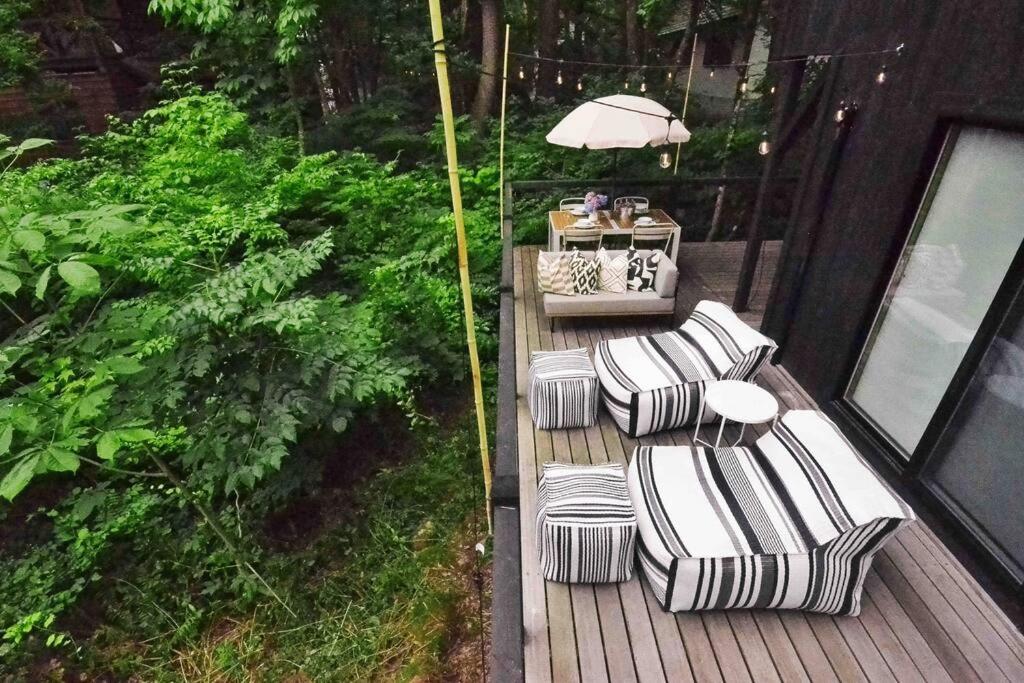 an outdoor deck with two chairs and an umbrella at Hakuba Cottage Karamatsu in Hakuba