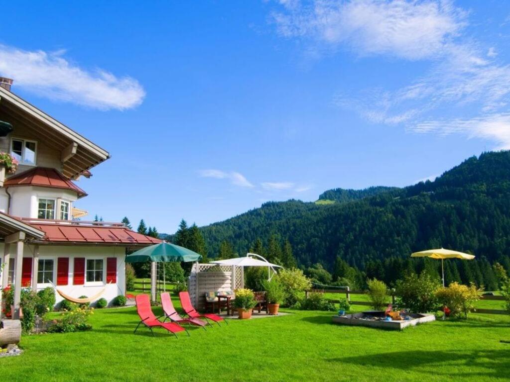 um quintal com cadeiras e guarda-sóis em frente a uma casa em Tranquil holiday home with large garden em Balderschwang