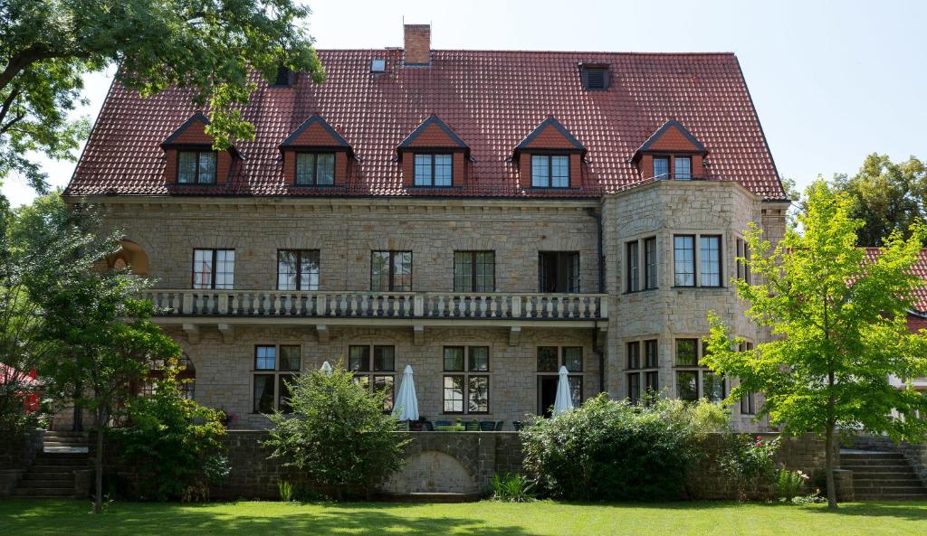 une grande maison en briques avec un toit dans l'établissement Parkhotel Unter den Linden, à Halberstadt