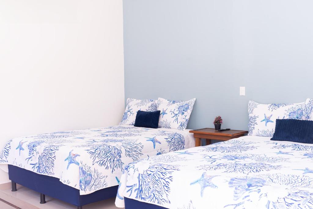 - une chambre avec 2 lits avec des draps bleus et blancs dans l'établissement Estancia Florencia H#4, à Tela
