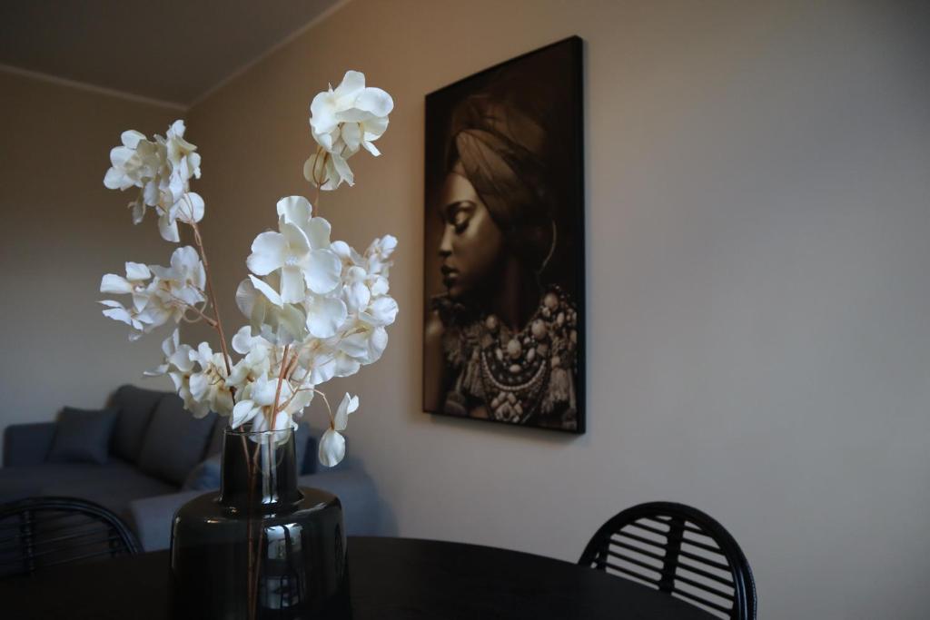 um vaso com flores brancas sobre uma mesa com uma pintura em De Stadsoase Tilburg em Tilburg