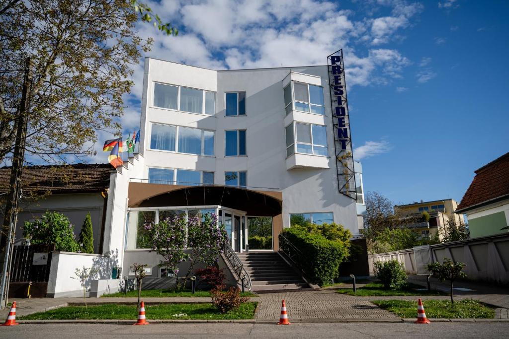 a white building with orange cones in front of it at Hotel President in Timişoara