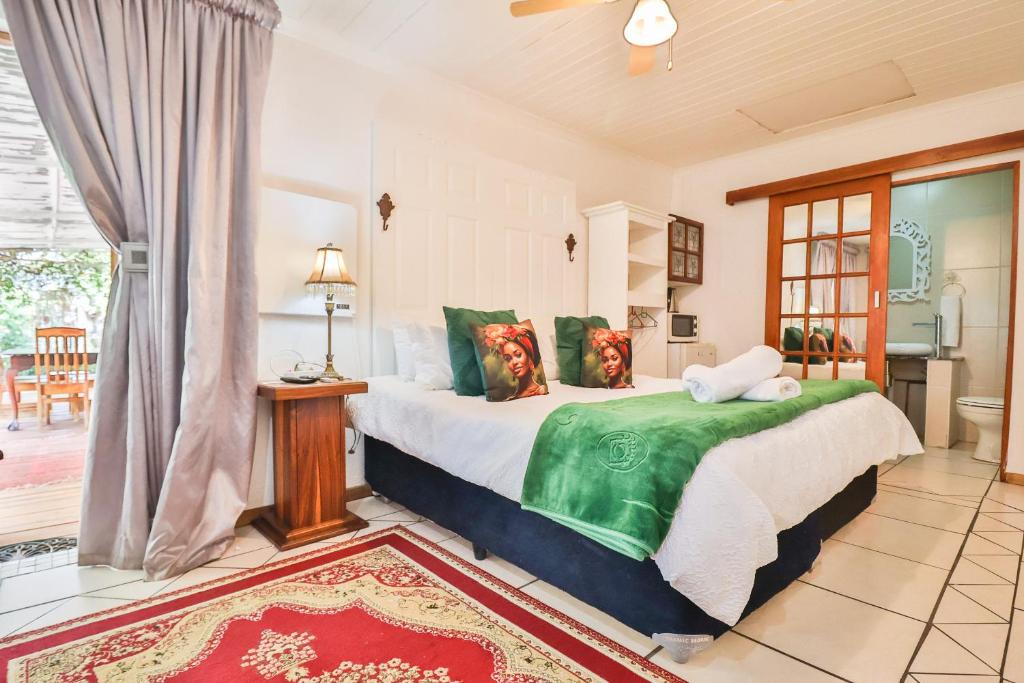 1 dormitorio con 1 cama grande con almohadas verdes en Snooze-A-Lot Guesthouse, en Secunda