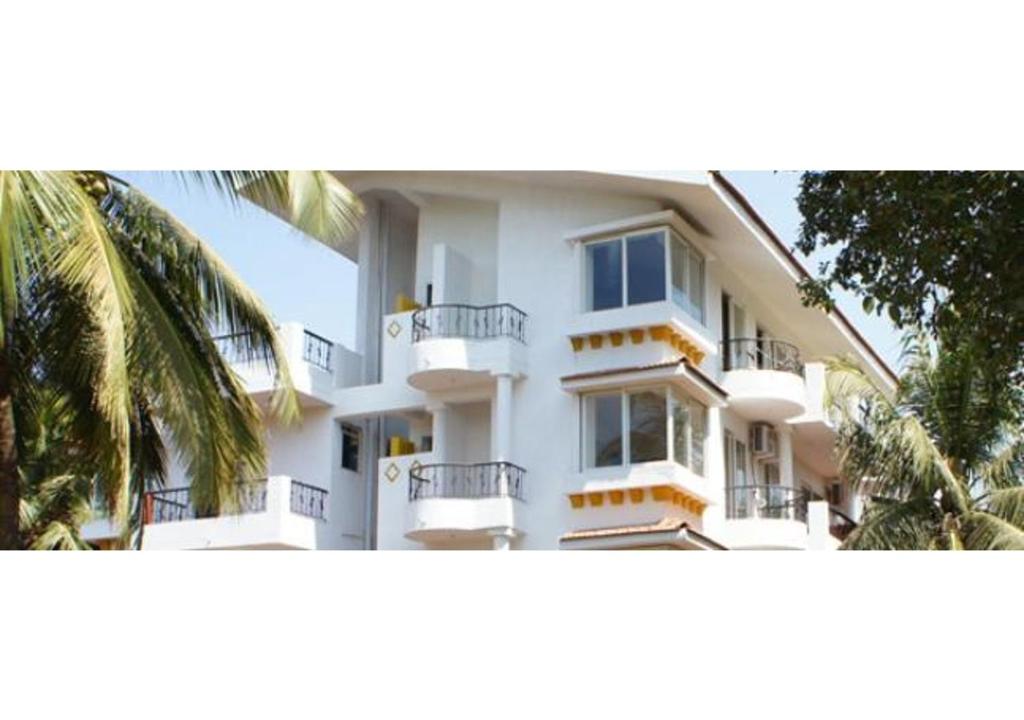 un edificio de apartamentos blanco con balcones y una palmera en AQUAVISTA at CasaPhilomena, en Calangute