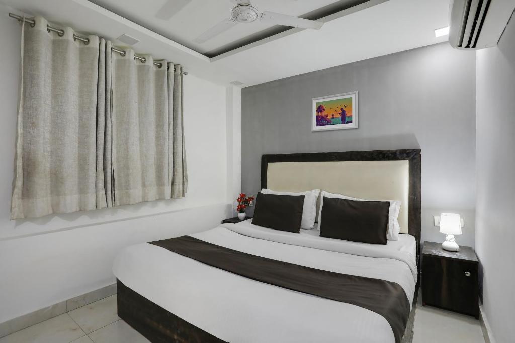 a bedroom with a bed with white walls and a window at Super OYO Hotel Mannat Near Lotus Temple in New Delhi